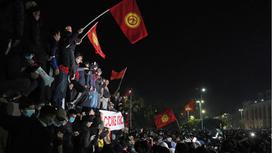 толпа людей стоят с флагами Кыргызстана на митинге в Бишкеке