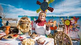 Женщина за столом с самоваром и праздничными блюдами