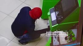 Мужчина в куртке и красном капюшоне сидит перед банкоматом