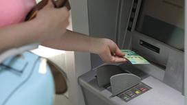 Женщина вводит деньги в банкомат
