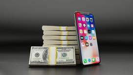 Айфон стоит рядом с пачками долларов