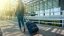 Девушка с рюкзаком и чемоданов идет в аэропорт