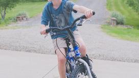 Мальчик едет на велосипеде по дороге