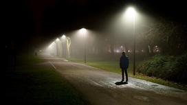 Мужчина идет по освещенной фонарями улице