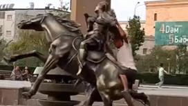 Пьяный мужчина падает вместе со скульптурой лошади