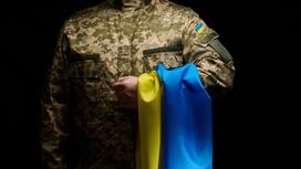 Солдат держит в руках флаг Украины