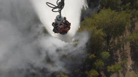 Вертолет сбрасывает воду на горящий лес