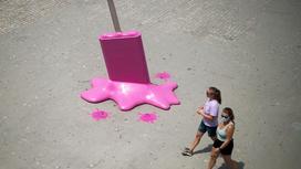 Две девушки идут мимо гигантской инсталляции мороженого на пляже