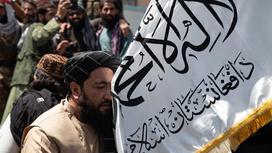 Мужчины несут флаг движения "Талибан"