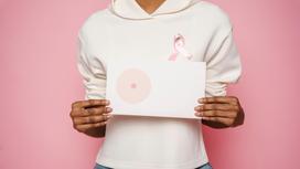 Женщина в розовой кофте держит рисунок