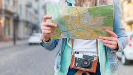 Девушка держит в руках карту с изображением местности