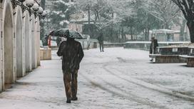 Мужчина идет с зонтом в снегопад