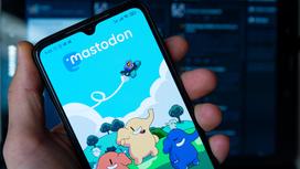 Мужчина держит смартфон с открытым приложением Mastodon