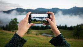 Девушка снимает на мобильный красивый пейзаж