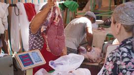 Женщина покупает мясо на рынке