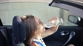Девушка в машине пьет воду