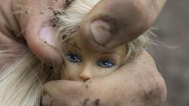 Рука сжимает куклу