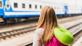 Девушка с рюкзаком смотрит на поезд