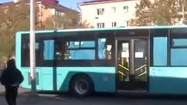 Мужчина проходит возле голубого автобуса