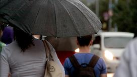 Люди с зонтами идут по улице