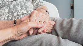 Женщина держит за руку бабушку