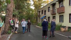 Люди стоят на улице перед домом в Усть-Каменогорске