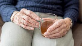 Пожилая женщина держит в руках кружку чая