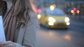 Девушка стоит на дороге спиной к такси