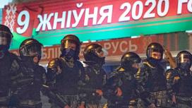 Силовики ОМОН стоят на фоне надписи о выборах в Беларуси