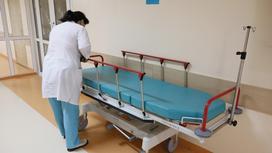 Медсестра стоит возле каталки в коридоре больницы