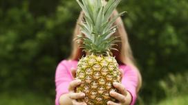 Девушка держит в руках большой ананас
