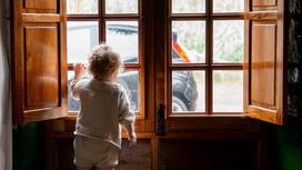 Ребенок стоит возле окна