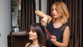 Парикмахер стрижет девушке волосы