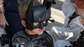 Мальчик в костюме Бэтмена среди детей