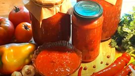 Красный соус в банках и в креманке, помидоры, сладкий и горький перец, зелень на столе