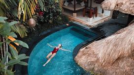 Девушка плавает в бассейне на Бали