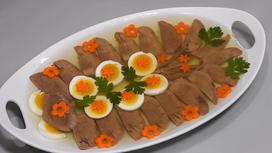 На сервировочном блюде заливное из языка, декорированное вареной морковью, зеленью и яйцом