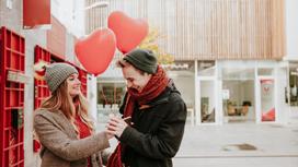 Парень и девушка держат воздушные шары в виде сердца