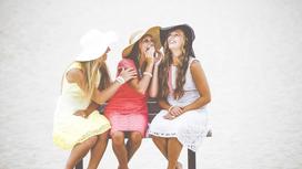 Три подруги в платьях и шляпках сидят на скамейке