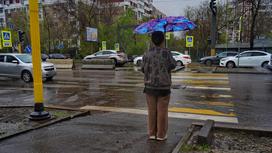 Женщина под зонтом возле дороги
