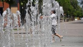 Мальчик идет среди струй воды в пешеходном фонтане