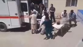 Человека доставили к машине скорой помощи после взрыва в Афганистане