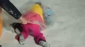 Дети в полиэтиленовом пакете готовятся скатиться со снежной горки