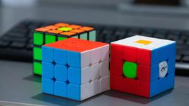 На столе лежат три кубика Рубика с разноцветными гранями