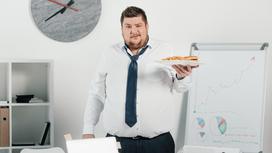 Полный мужчина в офисе ест фастфуд