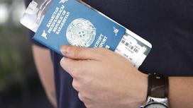 Мужчина держит казахстанский паспорт с билетом в руке