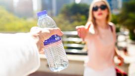 Мужчина передает бутылку воды женщине