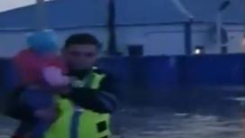 Полицейский выносит на руках ребенка из подтопленного дома в Атырауской области