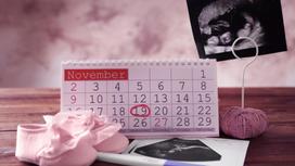 Снимок УЗИ, розовые пинетки и настольный календарь