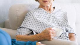 Пенсионерка сидит в кресле с чашкой чая